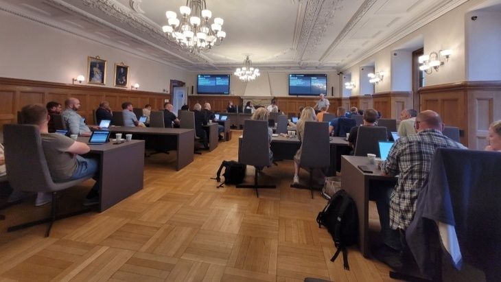 Møte i kommunesalen med politikere og skjermer foran i rommet